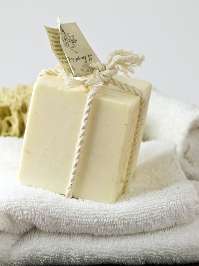 hero-img A close-up of handmade soap wrapped with natural rope on white towels, ideal for spa or relaxation themes.