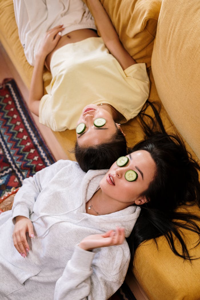 services-06 Two women enjoying a relaxing spa day with cucumber masks in a cozy home setting.